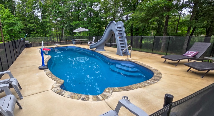 16 by 40 foot fiberglass pool with slide, diving board, and safety fencing